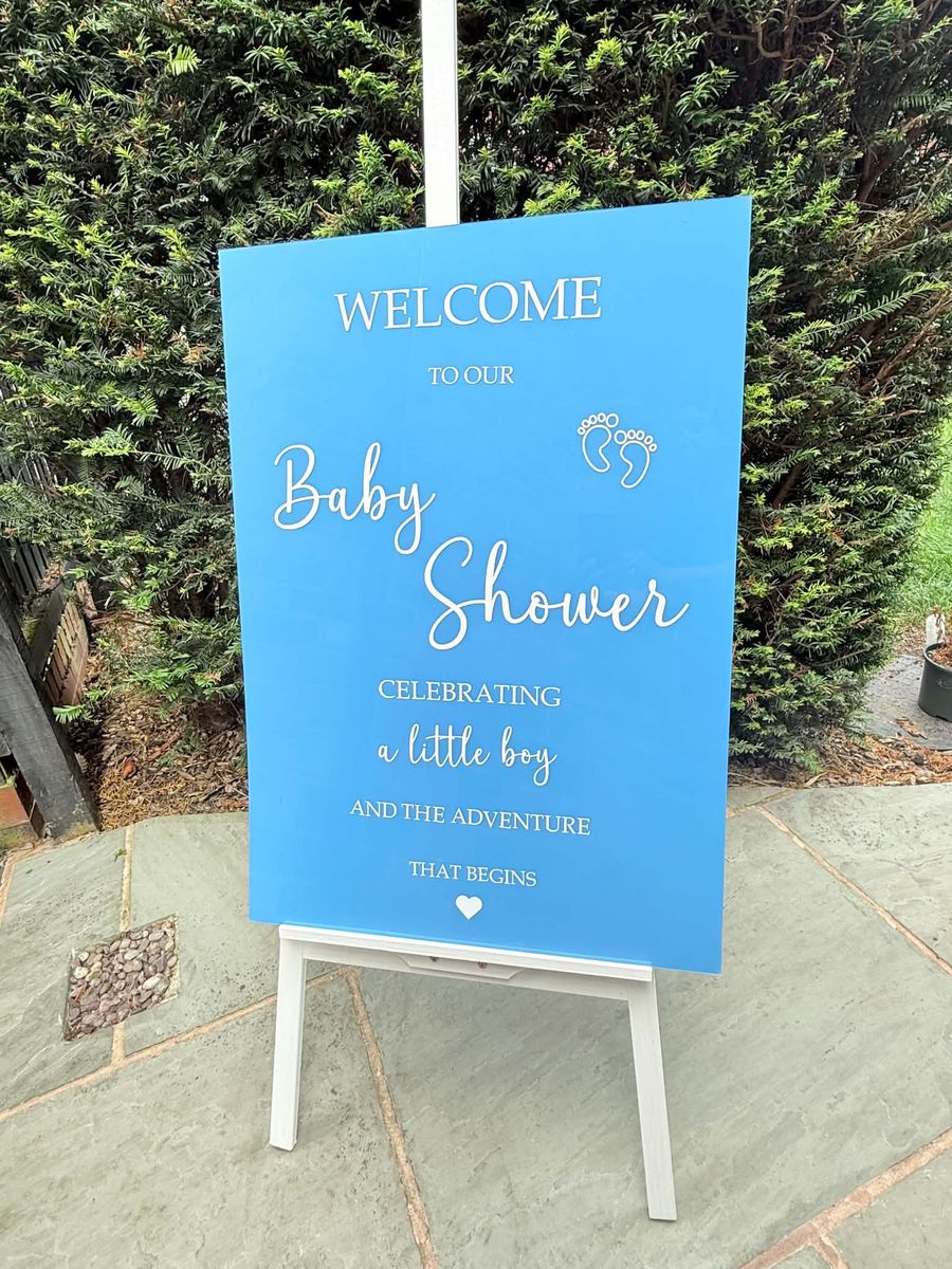 Blue baby shower welcome sign on a decorated easel