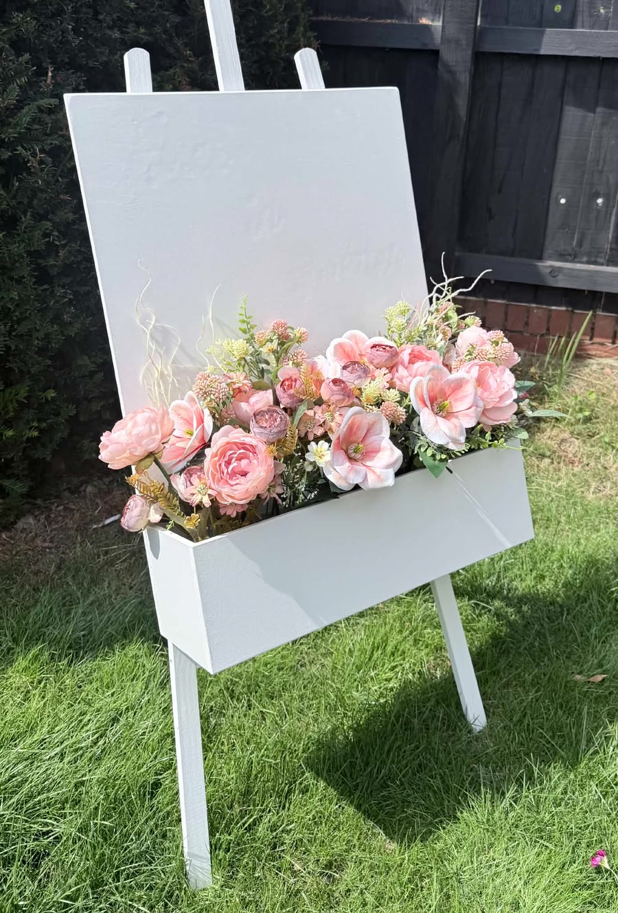 White celebration easel decorated with pink flowers